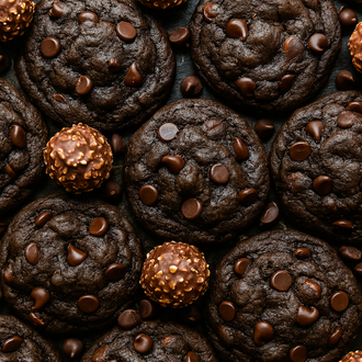 Chocolate cookies with chocolate chips and Ferrero Rocher candies on a dark surface